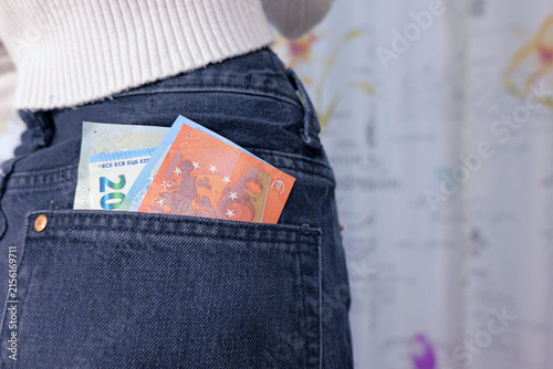Euro banknotes peeking from a jeans back pocket