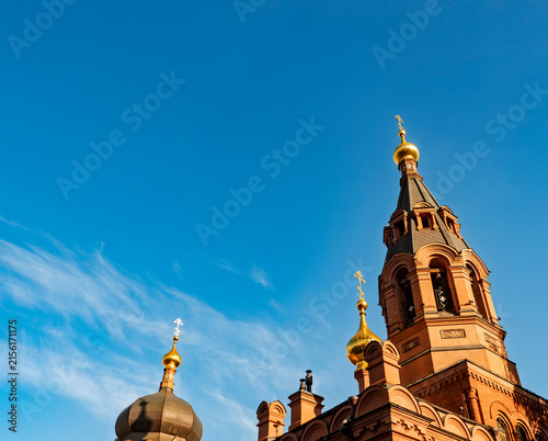 Фотография Russian Orthodox church with golden domes and red brick bell tower against blue