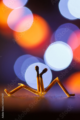 Two matchsticks shaped as human couple sitting together with bokeh background