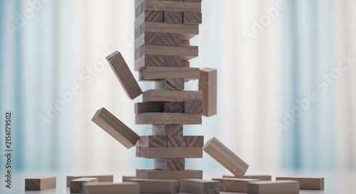 A precarious stack of wooden blocks falling over on a table representing risk and business strategy
