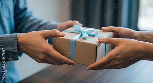 Close up of a person giving a small gift box wrapped in brown paper to another person