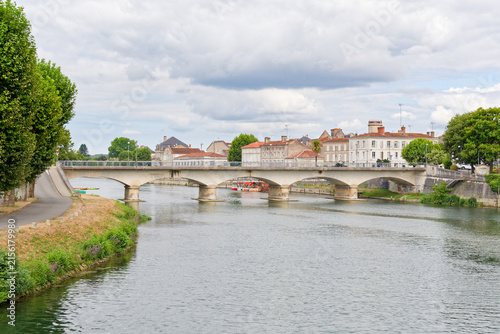 Obraz na plátne La Charente à Jarnac offre un décor paisible où le fleuve méandre doucement, bordé de quais historiques, de chais réputés et de parcs verdoyants invitant à la flânerie et aux loisirs nautiques