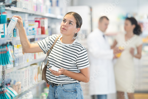 Bild auf Leinwand Attentive young girl choosing convenient health product standing next to shelves