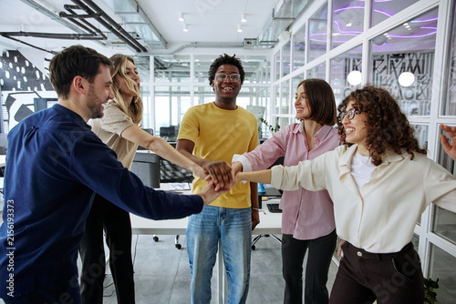 Obraz na plátně Diverse business team joining hands during a collaborative office meeting