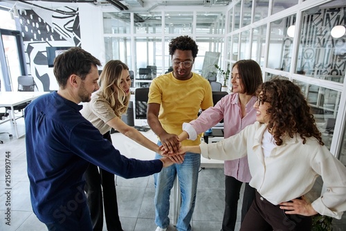 Obraz na plátne Diverse business team joining hands during a collaborative office meeting
