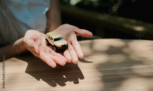 Fotografie Small beige toy car held in human hands with gentle feeling of care and apprecia