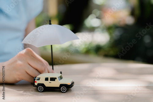 Konstfotografi Hand protecting toy car with umbrella, cheerful concept of vehicle insurance, sa