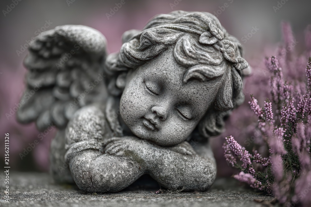 Fototapeta premium Weathered marble cherub at graveside closeup image