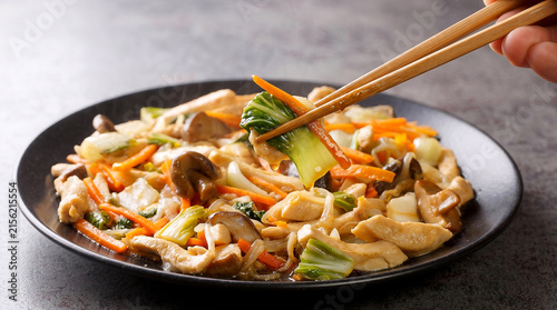 Delicious stir-fried vegetables and tofu on a plate with chopsticks, perfect for celebrating national chop suey day with healthy Asian cuisine