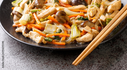Savor chicken chop suey with mushrooms and carrots on a dark plate with chopsticks, a tasty meal highlighting chop suey day for fans of Asian stir-fry dishes