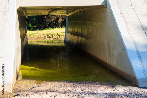 Cuadro en lienzo Concrete box culvert directing water flow beneath a rural road, featuring a stur