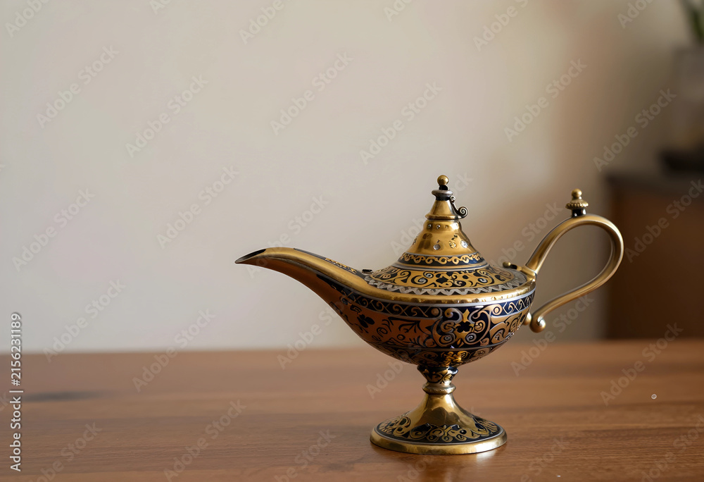 Fototapeta premium Ornate golden aladdin lamp with intricate blue and gold patterns on a wooden surface, magic and wish