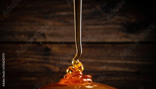 Liquid honey dripping onto golden pile of nectar.
