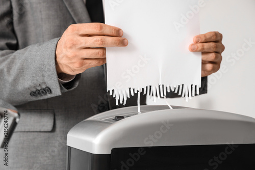 Foto Businessman shredding confidential documents for data protection and privacy in