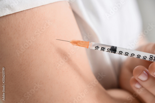 Fotografie Close up of a persons arm receiving an injection with a medical syringe, Healthc