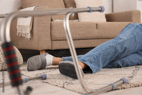 Legs of senior man lying on floor after fall with walker at home