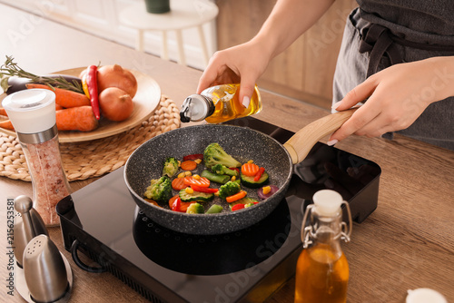 Woman frying vegetables wit...