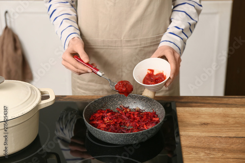 Young woman adding tomato p...