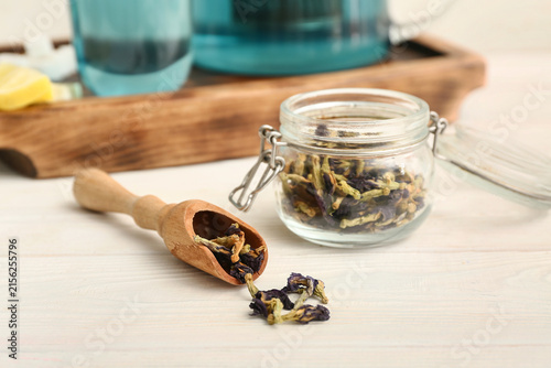 Bild auf Leinwand Jar and wooden scoop with butterfly pea flower tea on white background, closeup