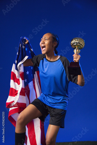 Konstfotografi African American female athlete in blue jersey raising trophy and draping Americ