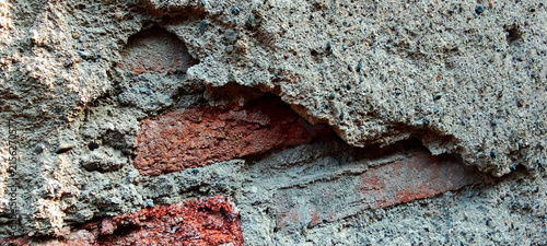 Damaged plaster revealing the texture of weathered red brickwork.