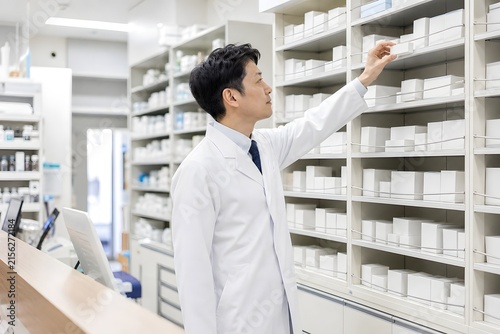 Fototapeta 薬局の棚から薬を取り出す薬剤師