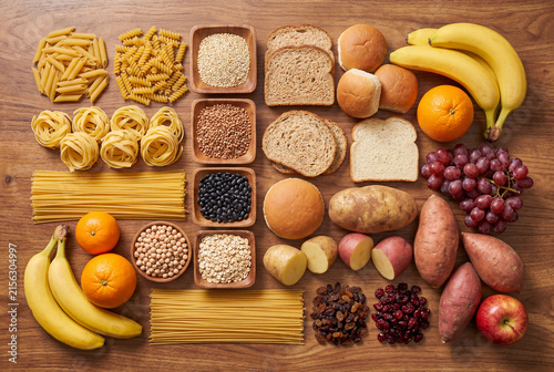 Overhead assortment of carbohydrate rich foods arranged on a wooden table surface