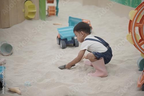 Toddler boy playing with shovel in indoor sandbox