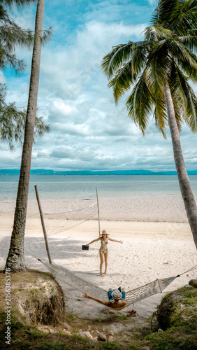 Top view of couple tourist are in motion of relaxing stay under coconut palm tree at the the edge of the sea beach,  trip summer on vacation of couple lover