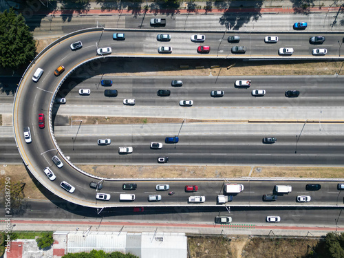 Drone view captures multi-lane highway traffic. Urban road network, modern city infrastructure with cars moving on a sunny day.