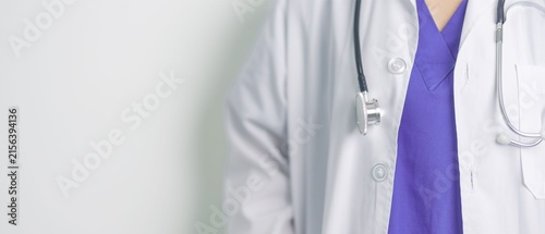 Doctor in White Coat and Purple Scrubs with Stethoscope on Light Background