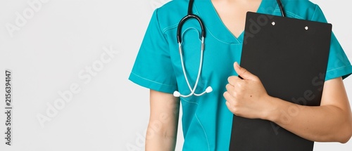 Doctor in Teal Scrubs Holding Clipboard with Stethoscope on Copy Space Background