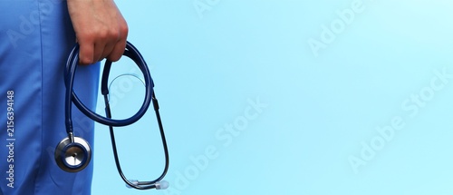 Doctor in Blue Scrubs Holding Stethoscope on Light Blue Background