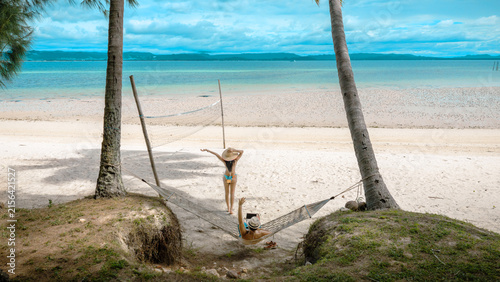 Top view of couple tourist are in motion of relaxing stay under coconut palm tree at the the edge of the sea beach,  trip summer on vacation of couple lover