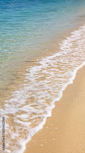 Gentle Waves Lapping on a Sandy Beach with Clear Blue Water Under Bright Sunlight