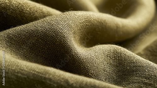 A detailed macro shot showing the surface folds of textured greenish brown linen fabric