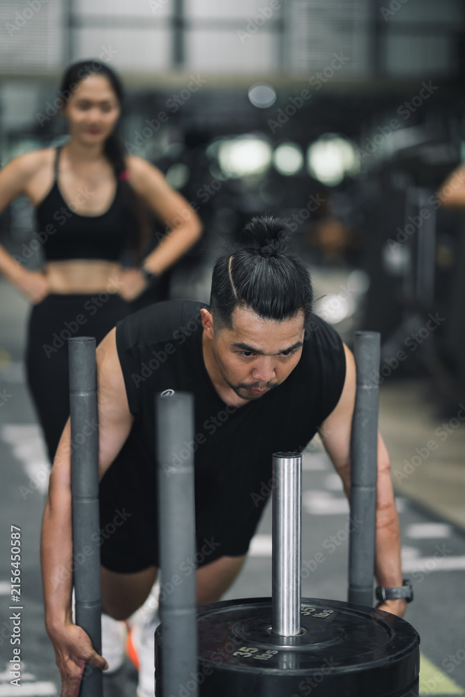 Fototapeta premium Strong Asia man doing prowler sled workout