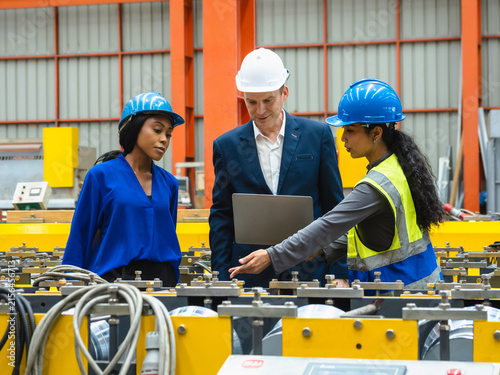 Diverse team industrial engineer executive manager with laptop discussing machinery operation modern factory highlighting teamwork inclusion corporate leadership smart manufacturing