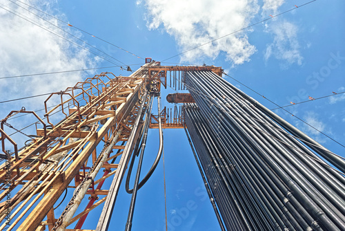 Bild auf Leinwand Drilling rig with top drive system (TDS) during tripping in the drill pipe to drill the hole in crude oil exploration operation with sunny blue sky background