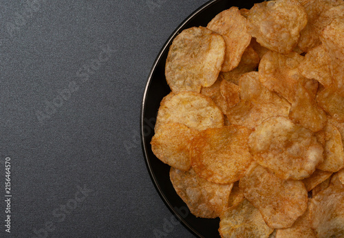 Spicy potato chips Close up tasty snack Chili spiced appetizer on a black plate background, horizontal view image detail of chip texture seasoning