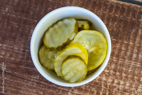 Top down view of sliced pickled cucumbers in small white ceramic bowl