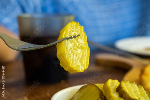 Obraz na plátne Close-up of pickled cucumber slice held on a fork at restaurant table