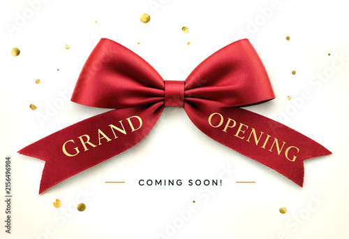 Beautiful red satin ribbon bow with grand opening text and confetti for celebration event announcement