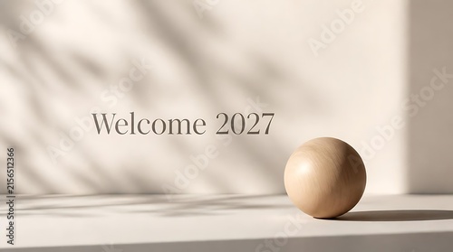 Welcome 2027 text with a wooden sphere and shadows.