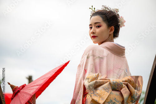 Obraz na płótnie Young Japanese geisha wearing a sweet pastel traditional kimono walks gracefully