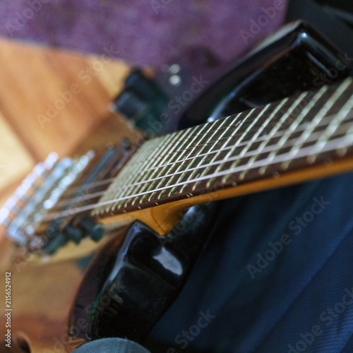 Electric guitar neck and fretboard held by a musician