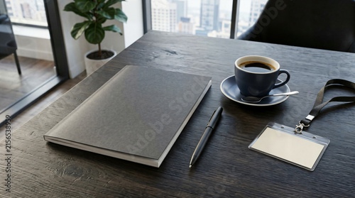 Office workspace with notebook coffee cup and blank id badge on dark desk