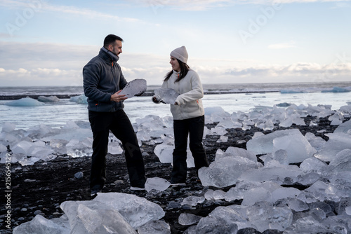 Fotografie Couple Interacting and Showing Large Ice Blocks on Diamond Beach