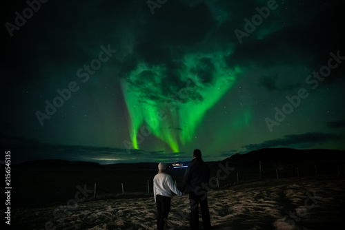 Wide Angle Landscape of Couple Under Swirling Green Aurora