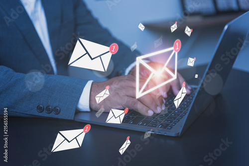 A professional businessman in a sleek suit works diligently on his laptop computer with visuals representing the concept of managing a busy email inbox.